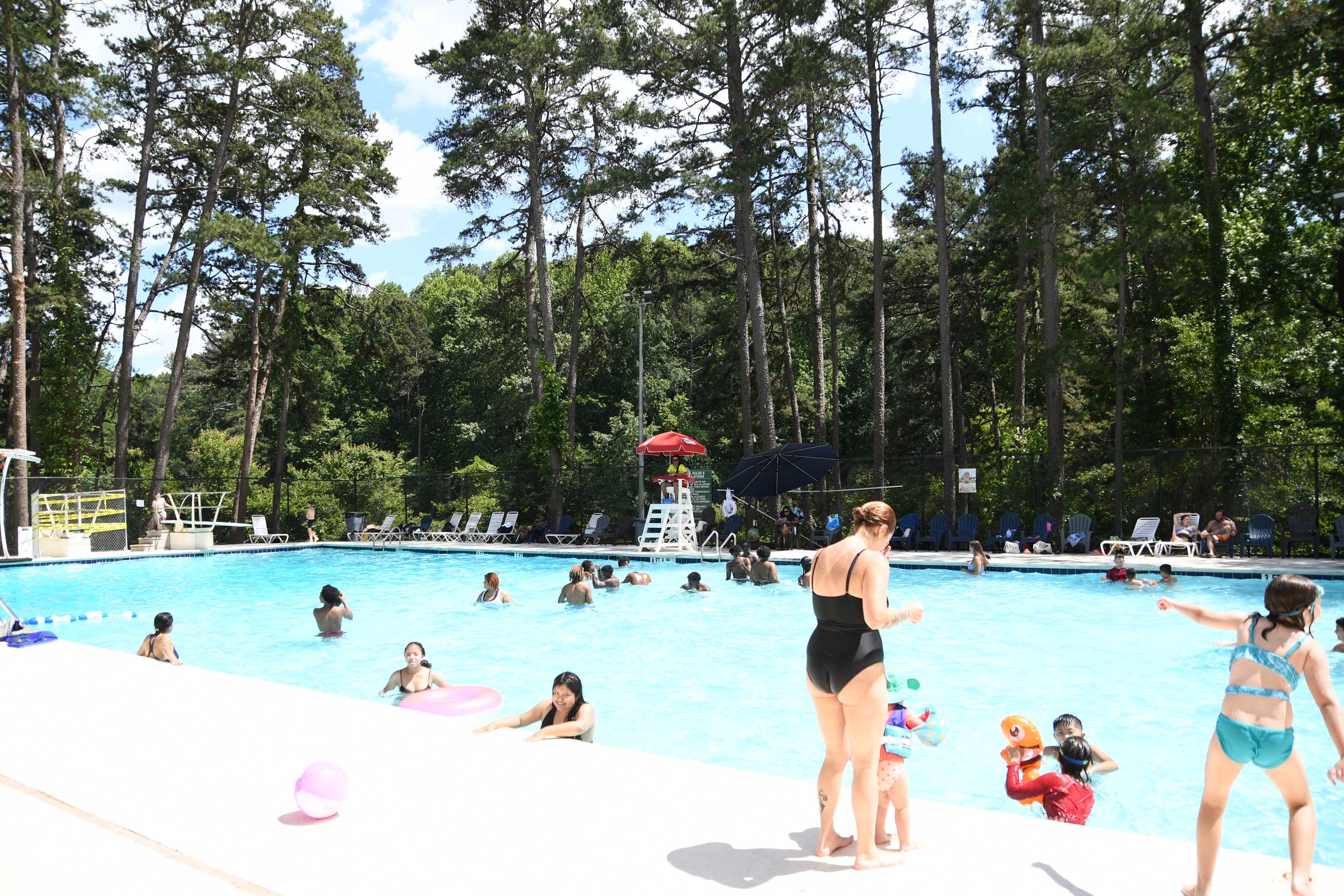 Kids and adults enjoying swimming in the pool on a warm day