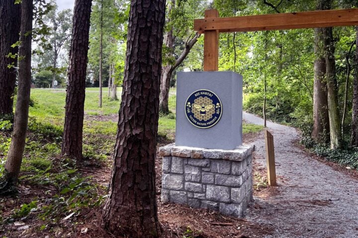 Sign says Bee Habitat Nature Preserve in front of forested area