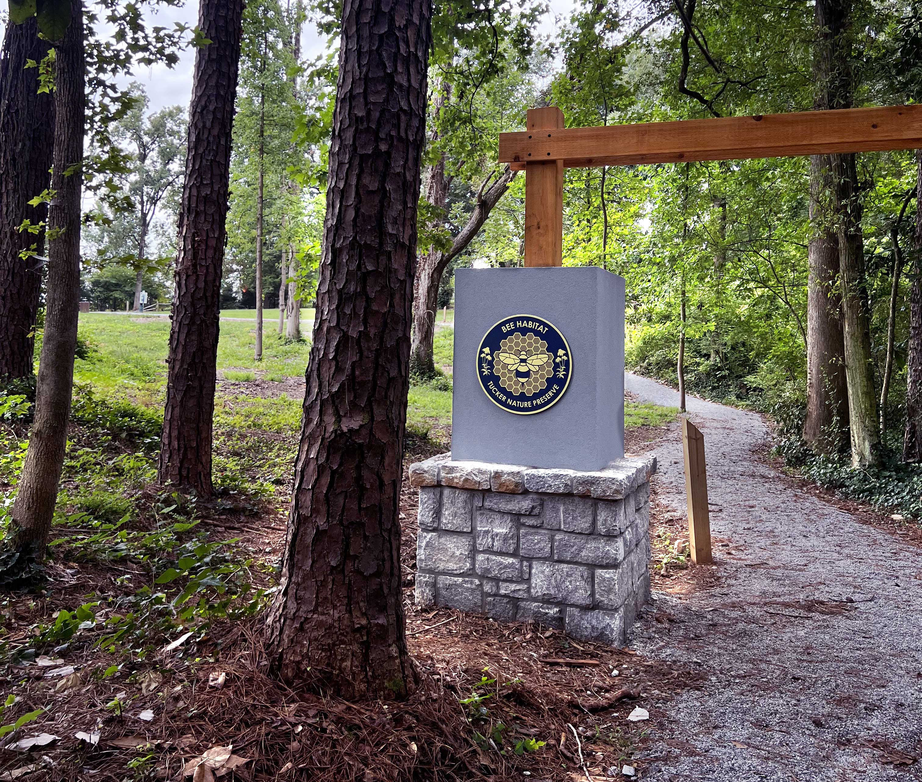 Sign says Bee Habitat Nature Preserve in front of forested area