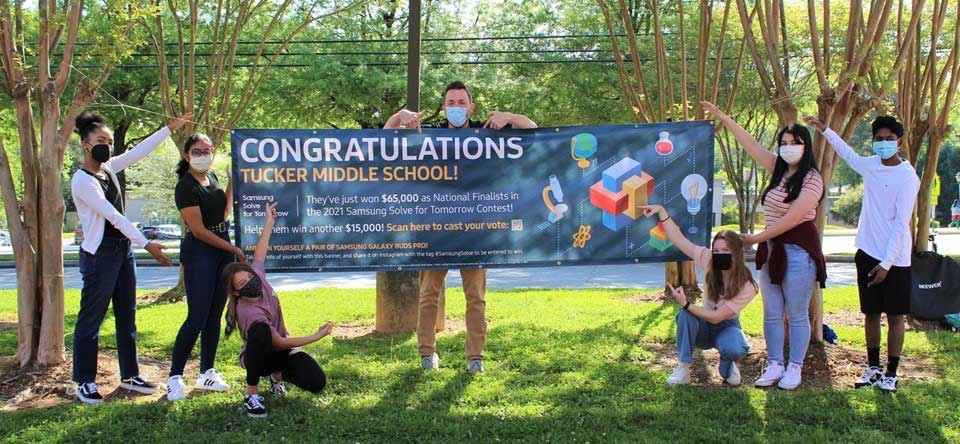 Middle school students pose with lage banner congratulating TMS on being finalists in nationwide contest