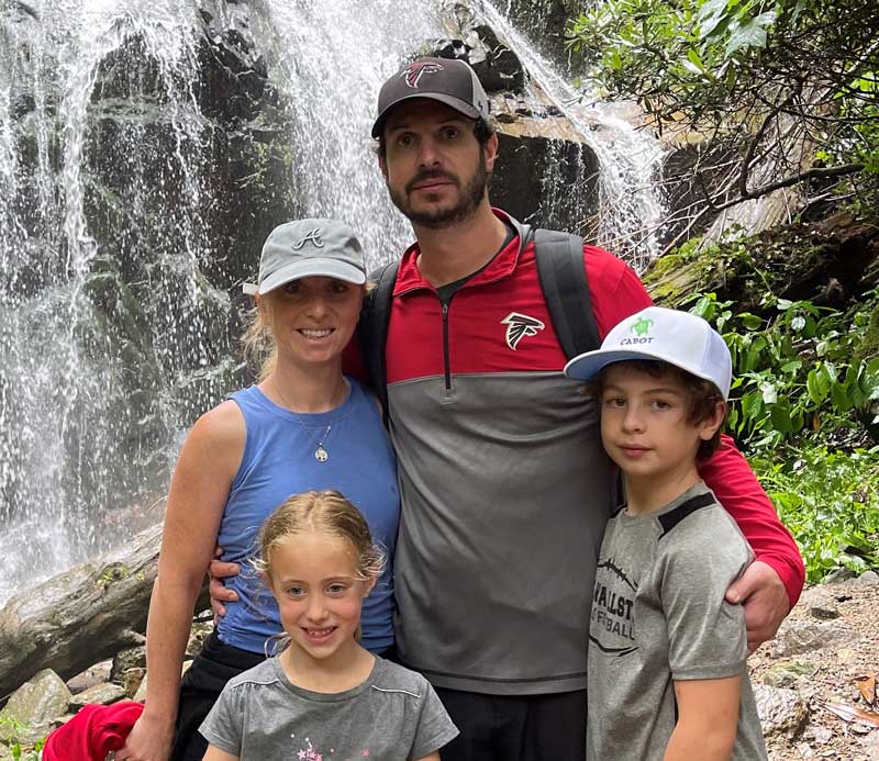 W. Teyf with their family outdoors in front of a waterfall