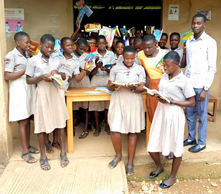 Group of girls in matching uniforms hold books in an African classroom