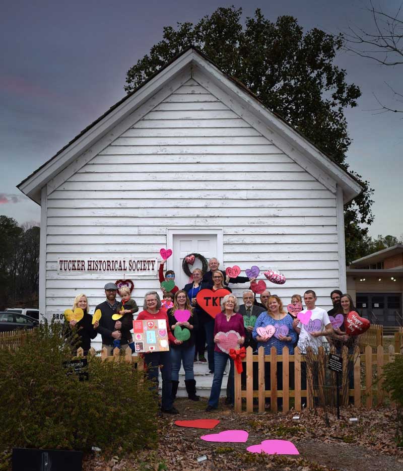 Group stands in front of old white wooden building