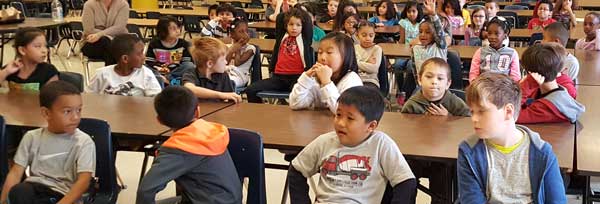 A large group of children sitting at long tables