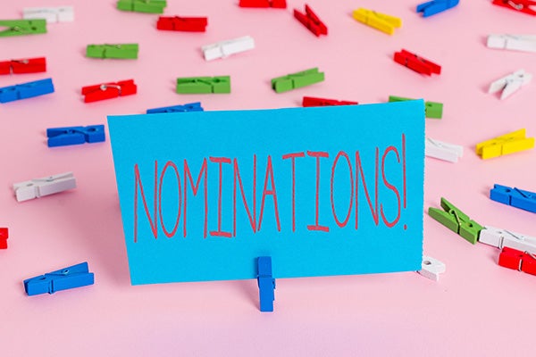 Writing note showing Nominations with multicolored clips in the background