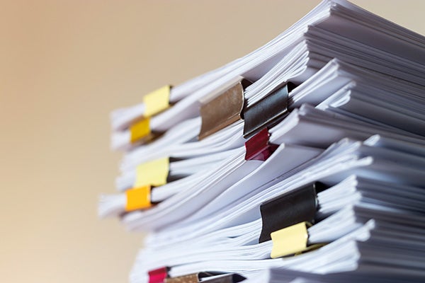 Piles of papers separated by colored binder clips.