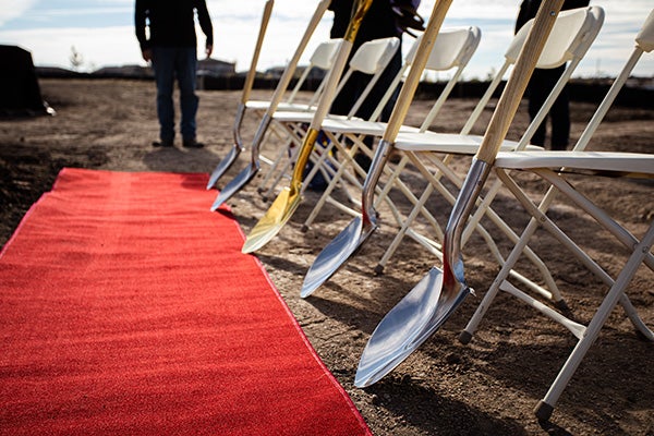 Construction ground breaking ceremony with shovels, chairs and red carpet.