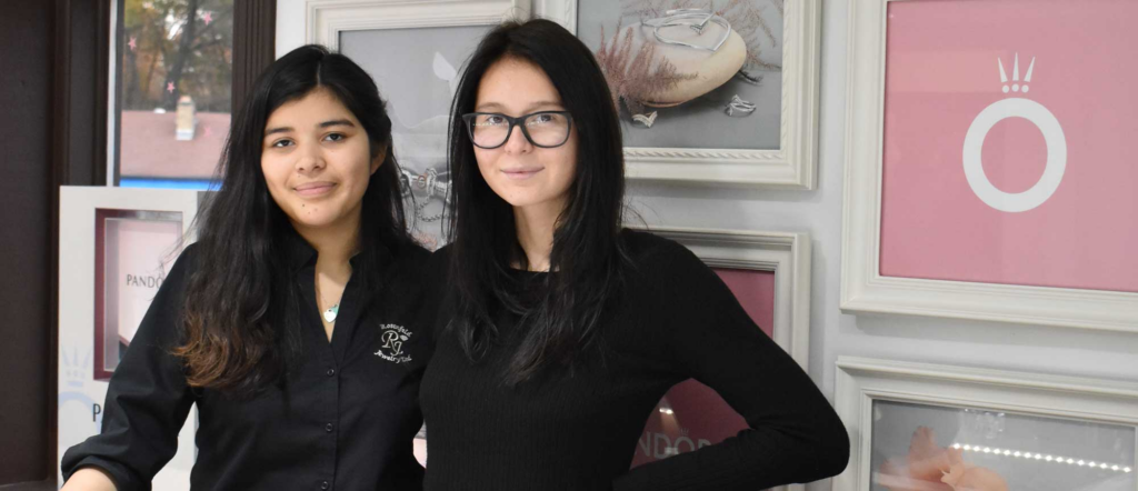 Two girls stand in font of business