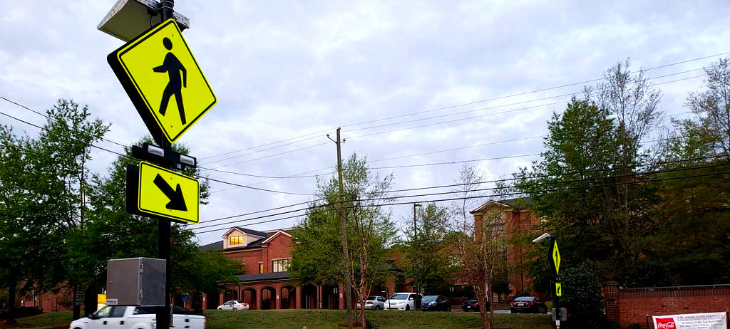 Red brick building in the distance, trees and a road between