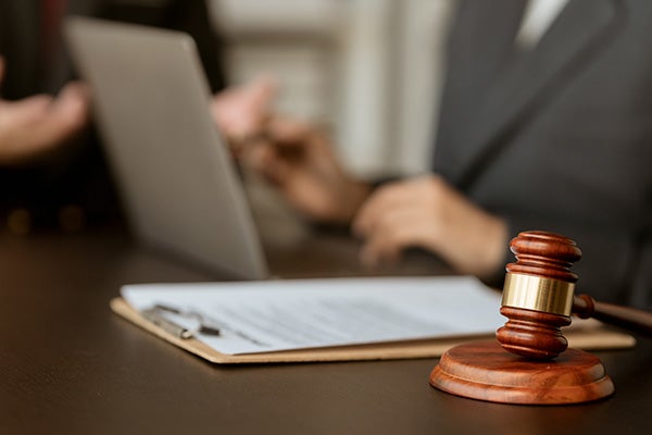 Person working at a conference table, with a judges gavel in the foreground