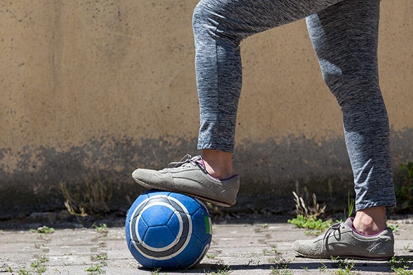 foot in street sneakers on top of soccer ball