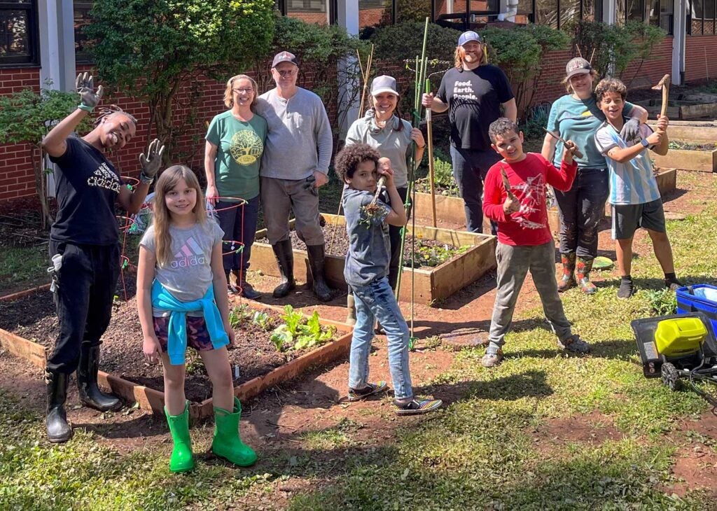 Children and a few adults pose among raised garden beds