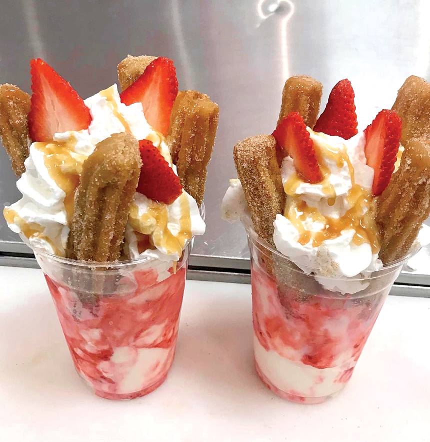 Ice cream topped with fresh churros, whipped cream and strawberries. 