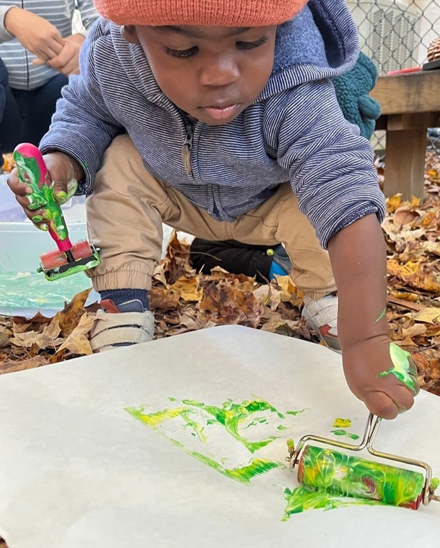 A child paints with a roller at Turning Sun